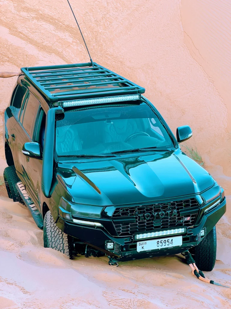 Toyota SUV buried nose-down in a sand dune with a recovery strap attached to the front