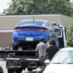 a blue car being loaded onto a flatbed truck