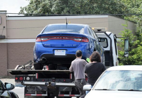 a blue car being loaded onto a flatbed truck