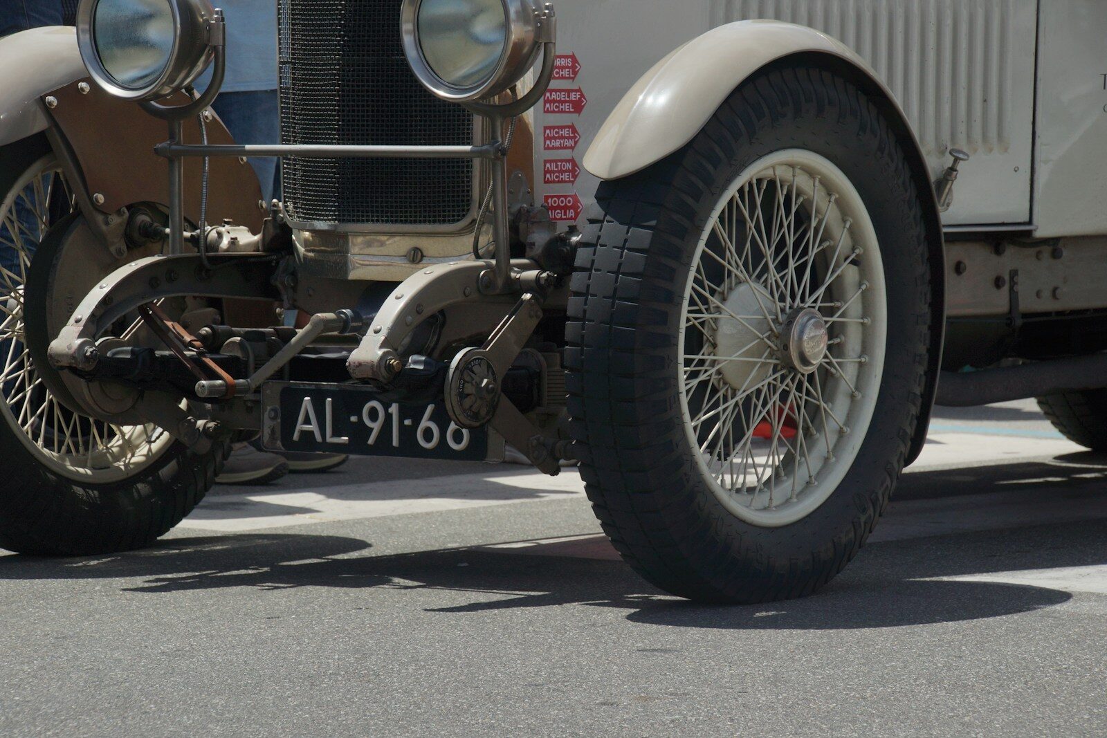 Vintage 1920s open car on wire-spoked wheels with exposed rear axle hardware and minimal fenders