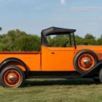 Golden Orange 1933 Ford V8 Roadster Pickup shown in side profile on a grassy lawn