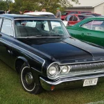 A black 1964 Dodge 330 sedan at a car show