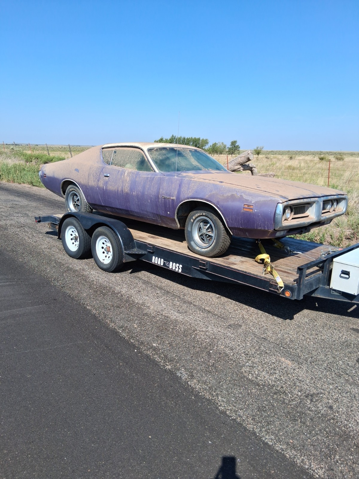 Dusty purple 1971 Dodge Charger riding on a flatbed trailer on open ground
