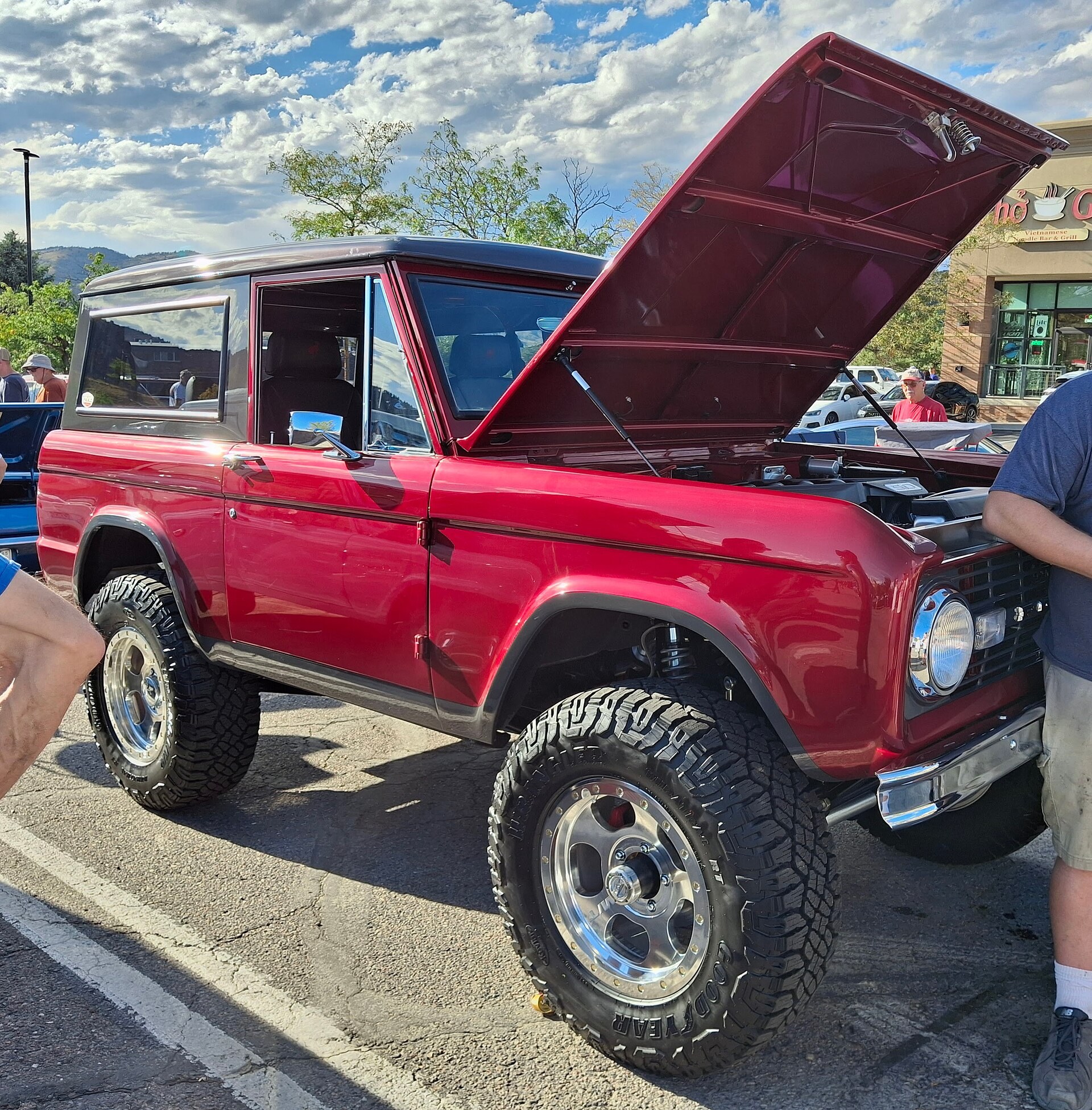 A red first-generation Ford Bronco at a classic car cruise