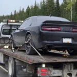 A black Dodge Challenger strapped to a flatbed tow truck on Highway 1 near Golden, B.C.