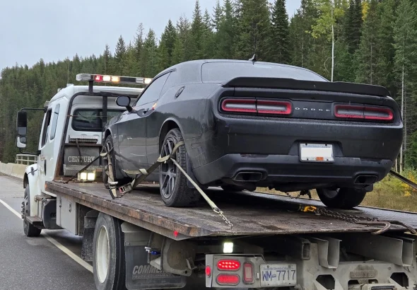A black Dodge Challenger strapped to a flatbed tow truck on Highway 1 near Golden, B.C.