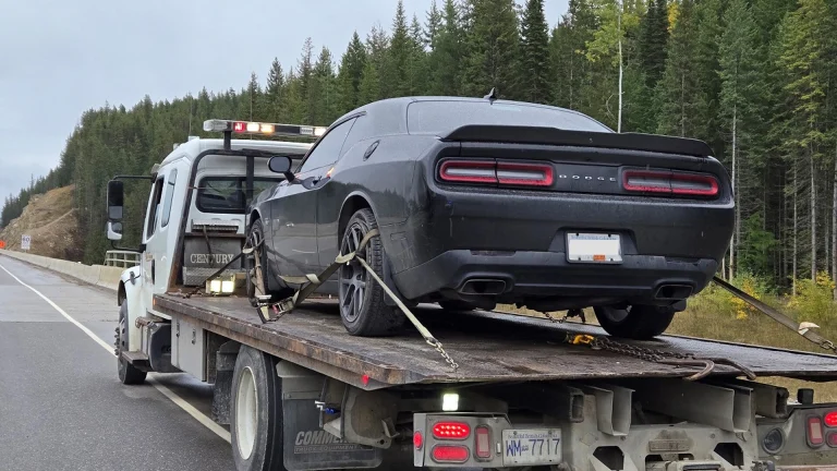 A black Dodge Challenger strapped to a flatbed tow truck on Highway 1 near Golden, B.C.