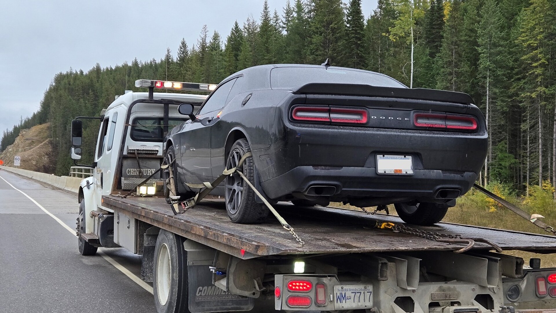 A black Dodge Challenger strapped to a flatbed tow truck on Highway 1 near Golden, B.C.