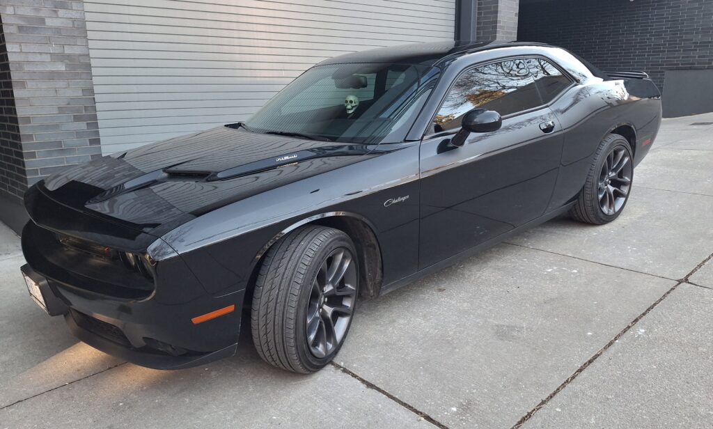 A black 2016 Dodge Challenger R/T parked beside a building