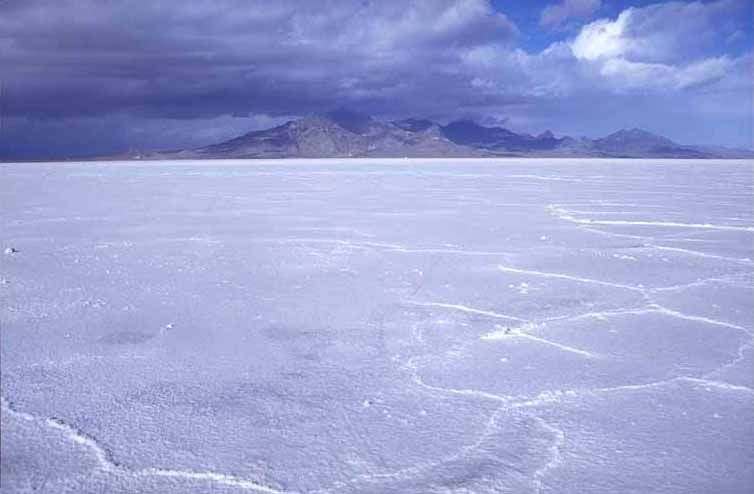 The flat white salt crust of the Bonneville Salt Flats in Utah with mountains on the horizon
