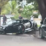 Black Bugatti Chiron with a crushed front end beside a curb and tree, from an @onlyindade Instagram reel