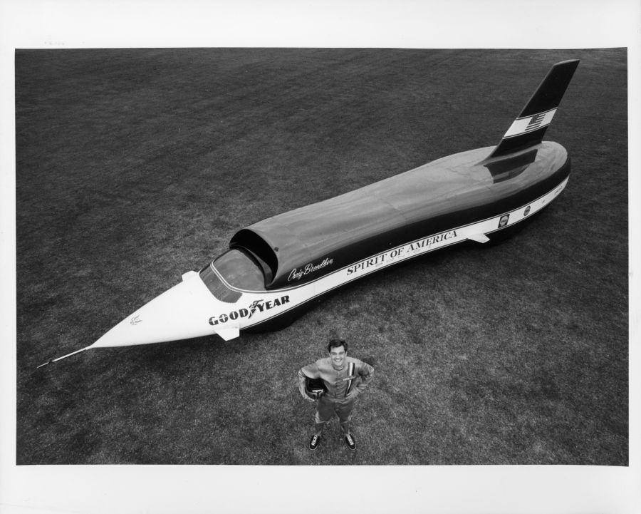 Black-and-white photo of Craig Breedlove standing in front of the four-wheeled Goodyear Spirit of America Sonic I jet car
