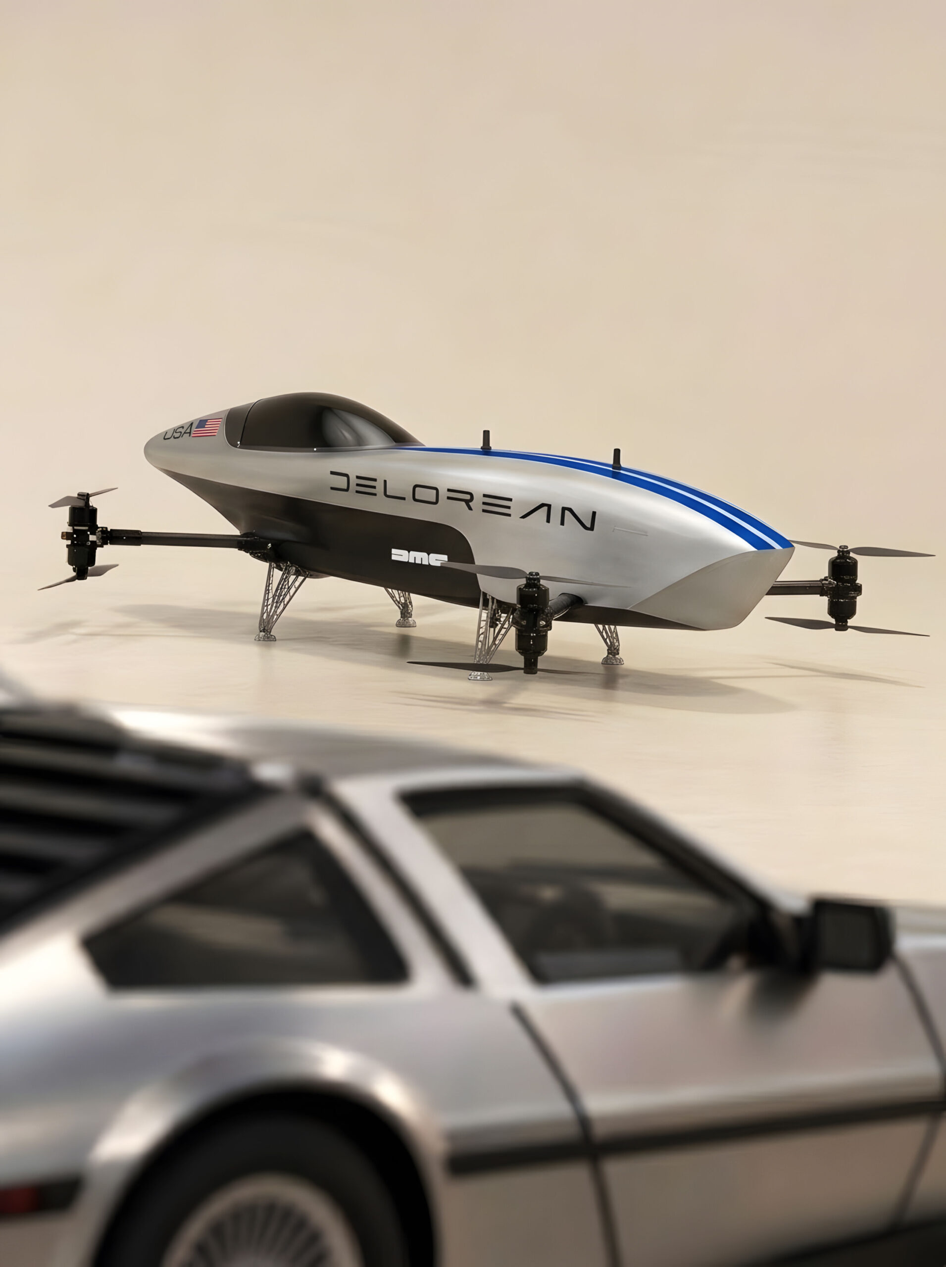 A silver Airspeeder aircraft with DeLorean lettering, blue stripes and a US flag decal photographed against a beige studio backdrop