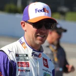 Denny Hamlin in a FedEx cap and driver suit on pit road