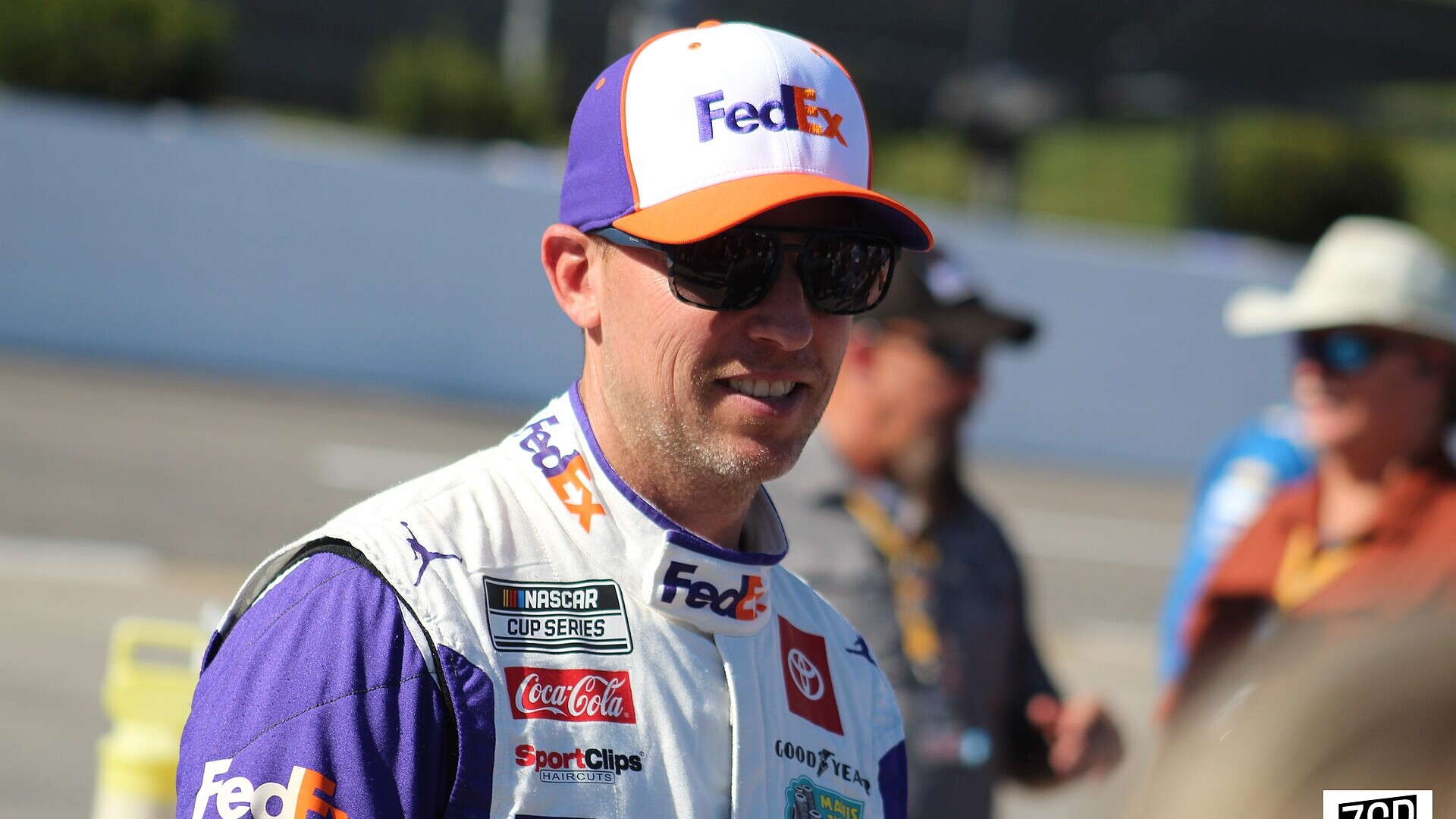 Denny Hamlin in a FedEx cap and driver suit on pit road