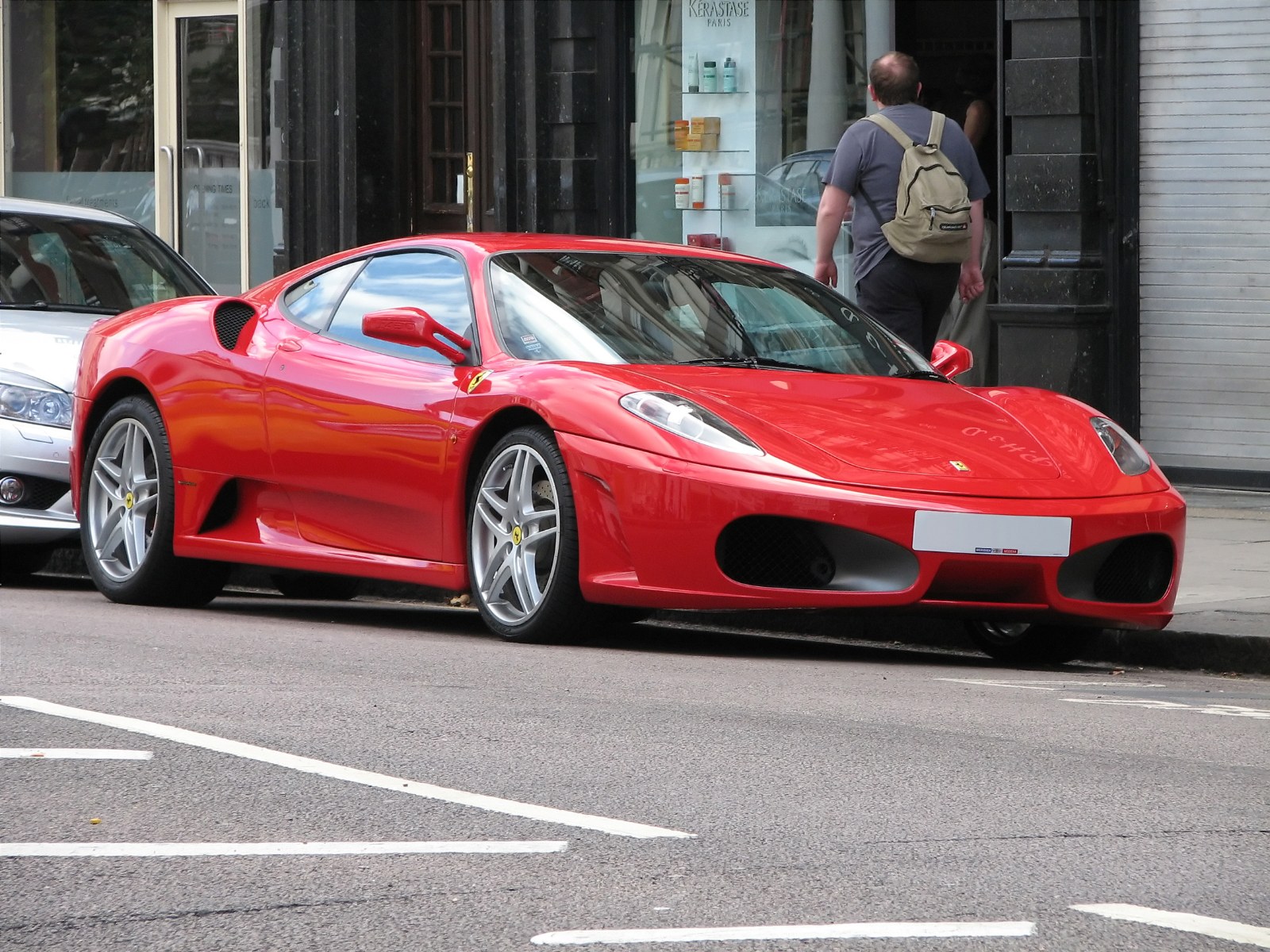 Red Ferrari F430 coupe parked on a city street
