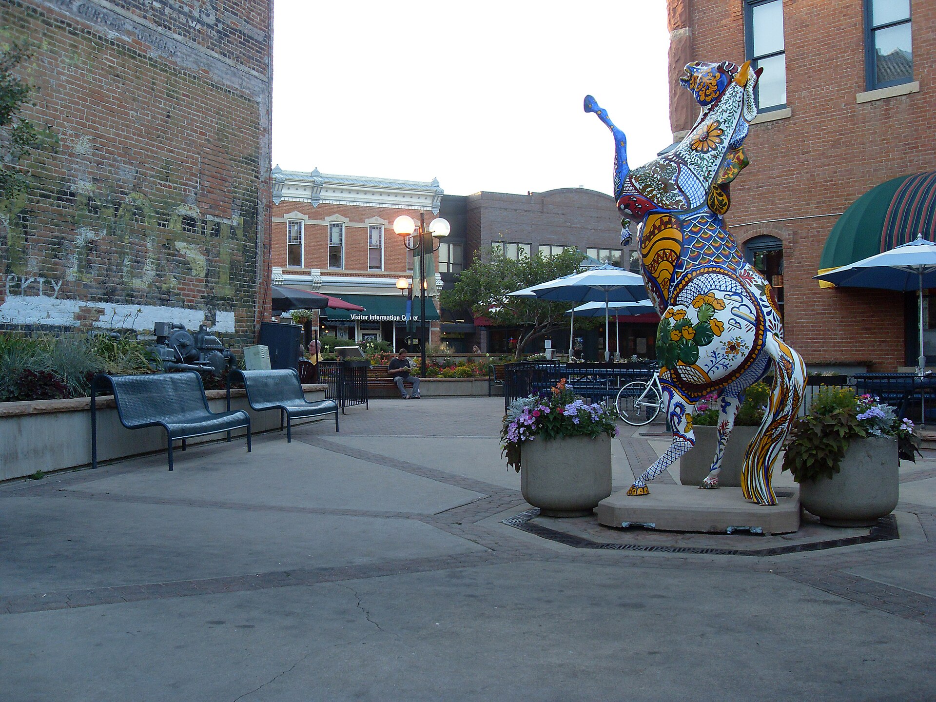 Old Town Fort Collins plaza with a mosaic horse sculpture, benches and brick storefronts