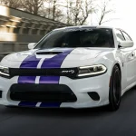 White car with purple stripes driving on road