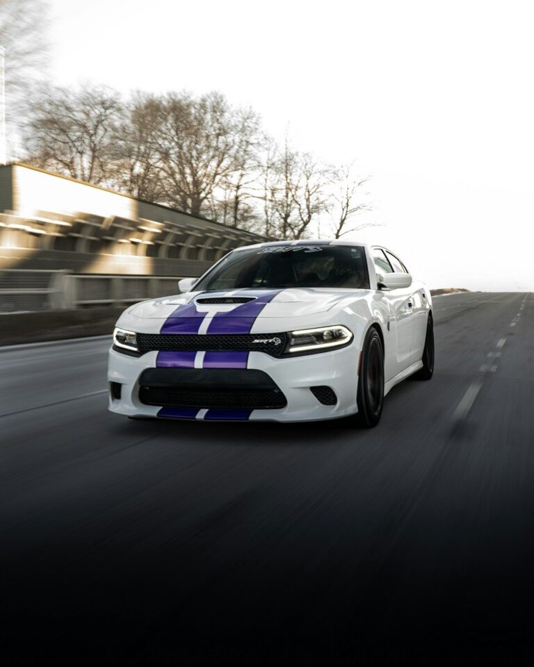 White car with purple stripes driving on road