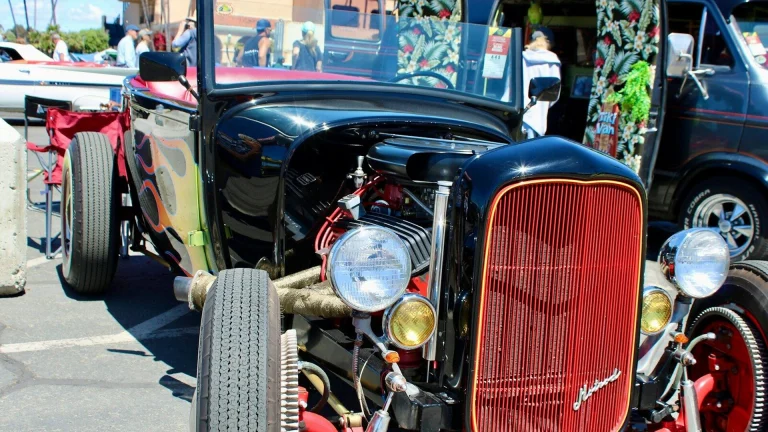A black hot rod roadster with a red grille at a car show