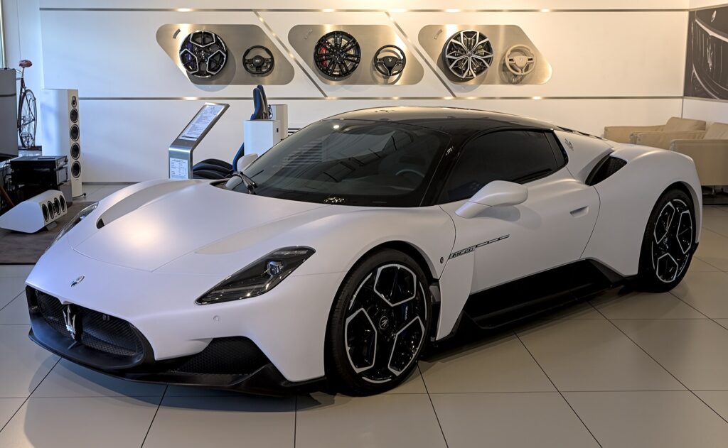A white Maserati MC20 on an auto show stand