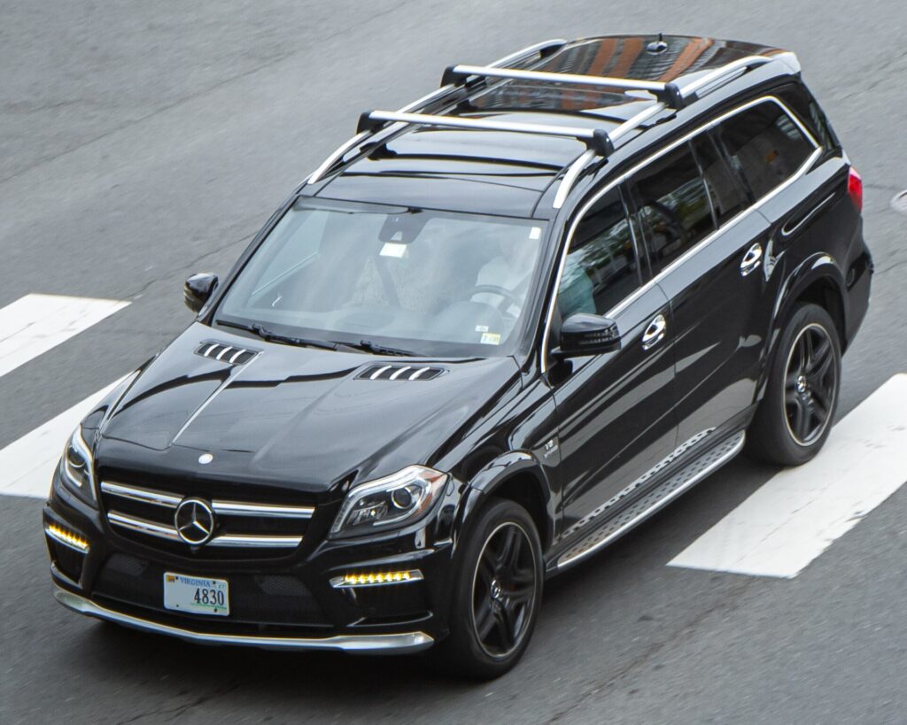 A black Mercedes-AMG GL63 SUV driving through a crosswalk