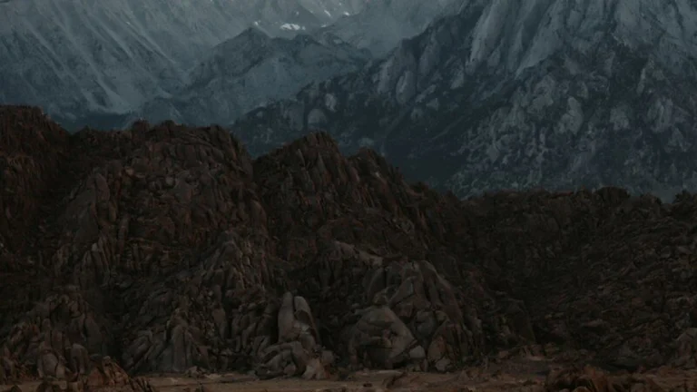 White truck driving on dirt road towards mountains