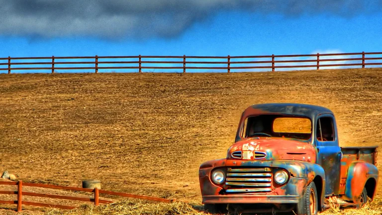 A weathered old Ford pickup truck abandoned in a field