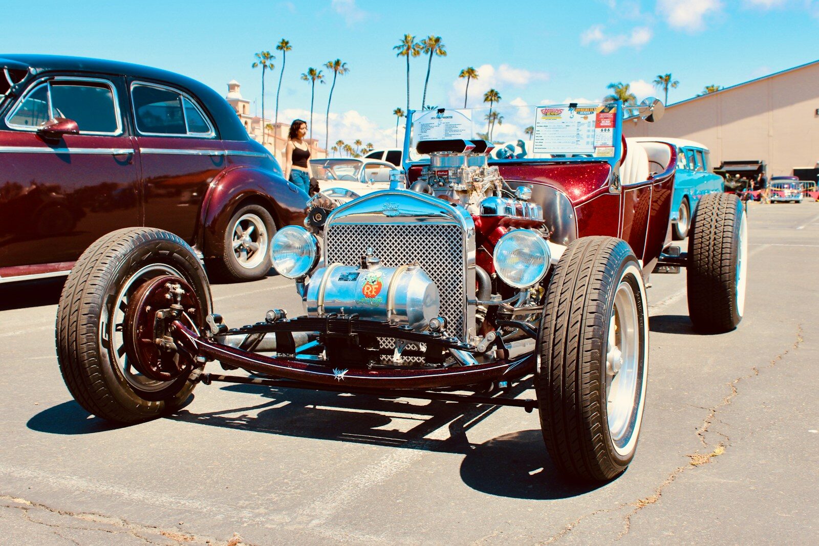 A red hot rod with a chrome radiator parked at an outdoor car show