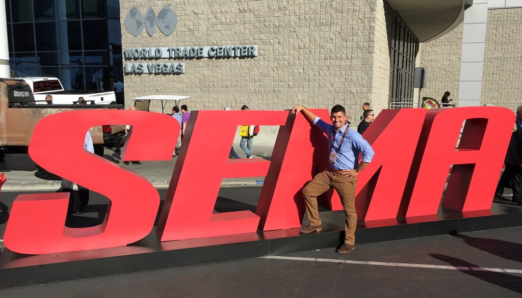 Visitor posing on the large red SEMA letters outside the Las Vegas Convention Center