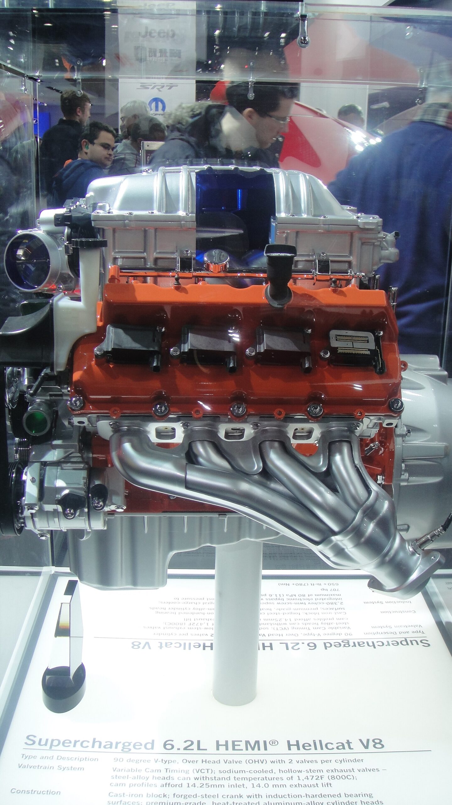 Orange supercharged 6.2-liter Hemi Hellcat V8 engine in a display case