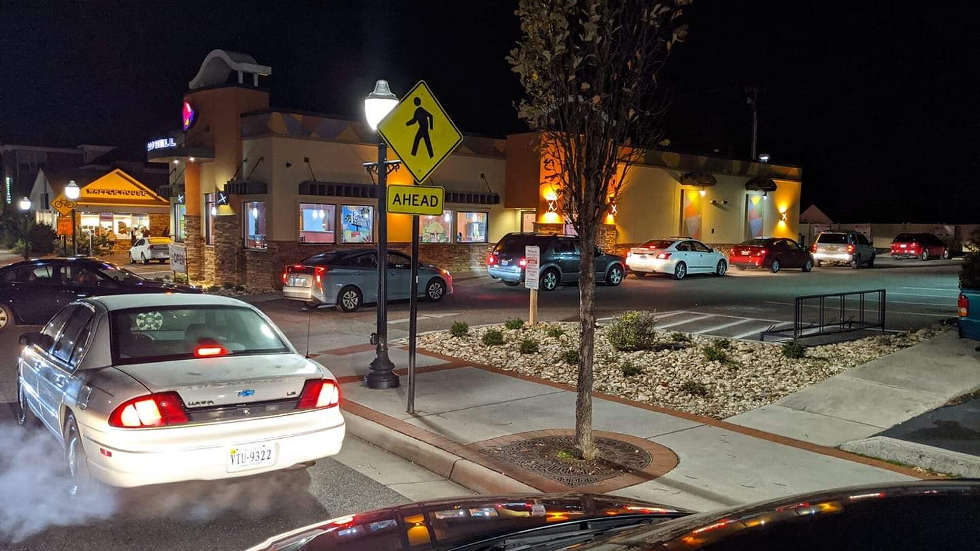 Cars lined up at a Taco Bell drive-thru at night