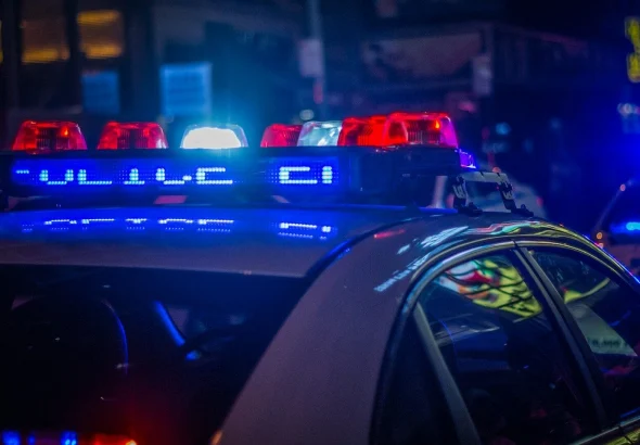 A police car with flashing red and blue emergency lights on a city street
