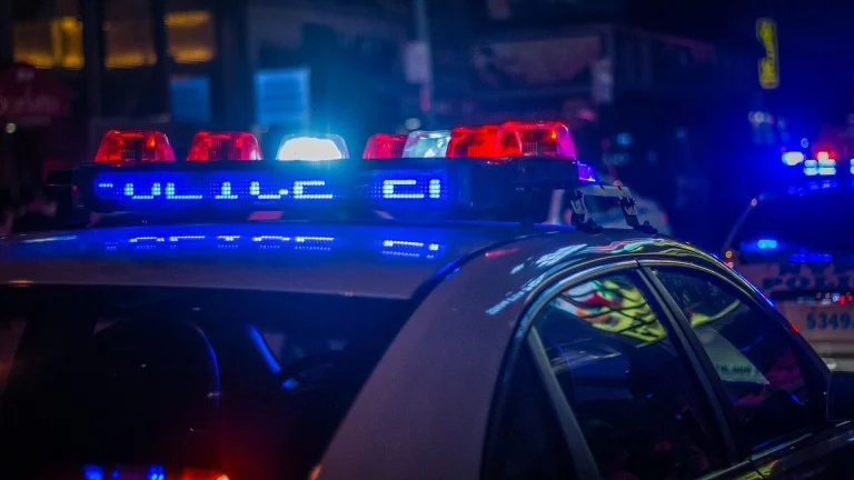 A police car with flashing red and blue emergency lights on a city street
