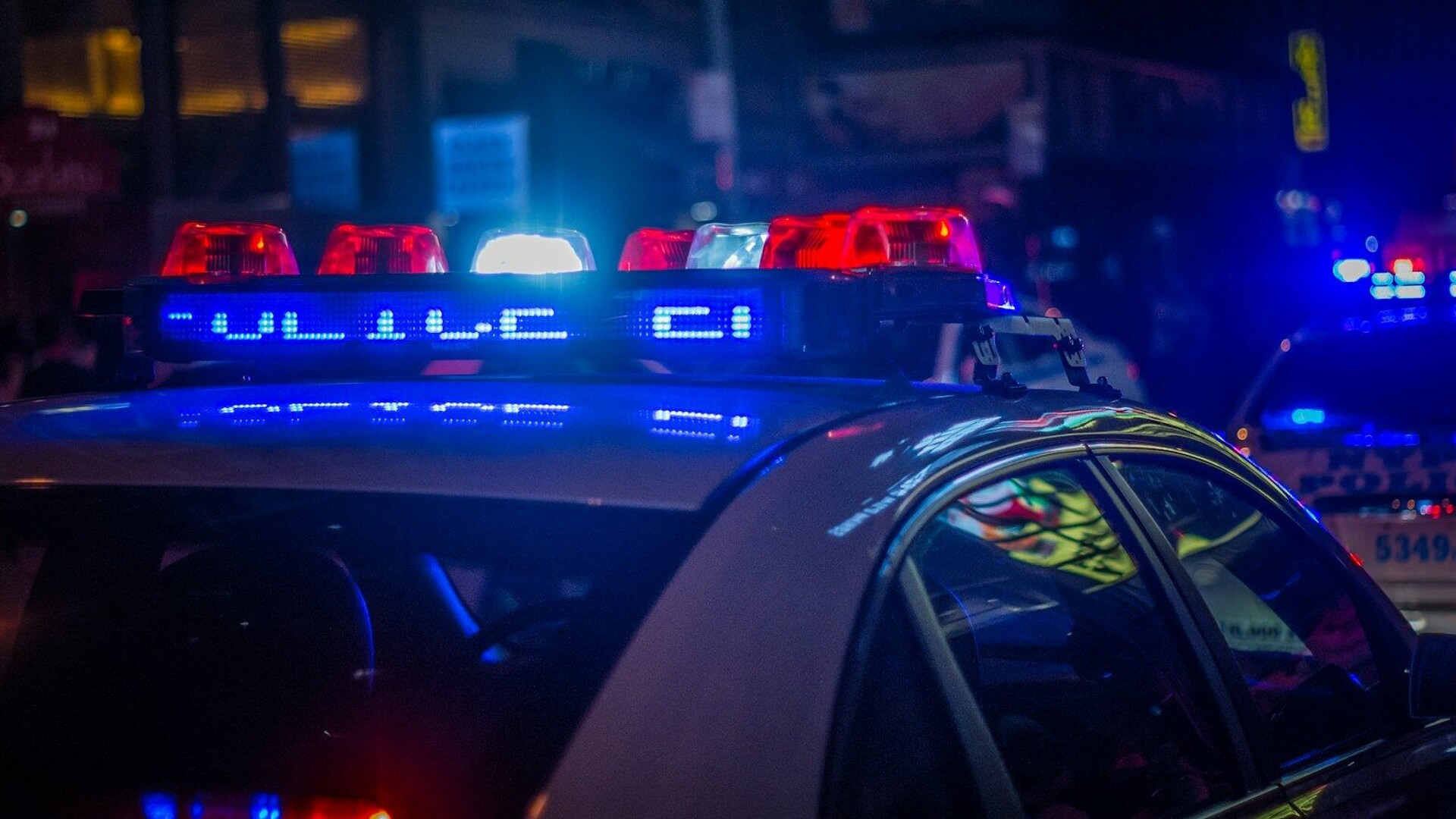 A police car with flashing red and blue emergency lights on a city street